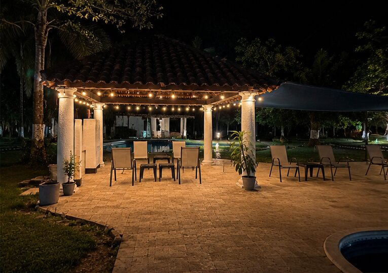 La pérgola con luces y mesa de comedor junto a la piscina