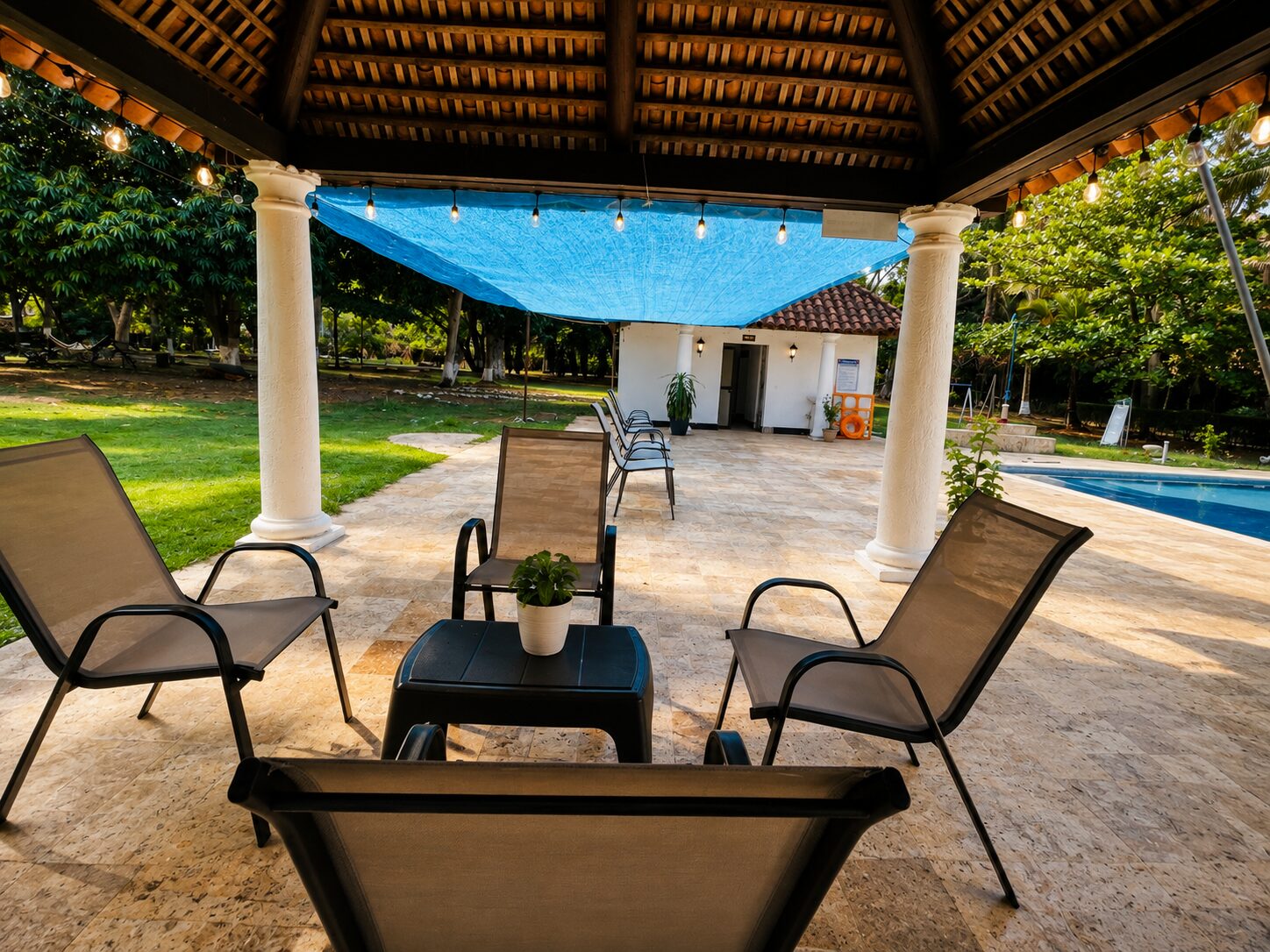 Terraza cubierta con sillas de descanso junto a la piscina, de día